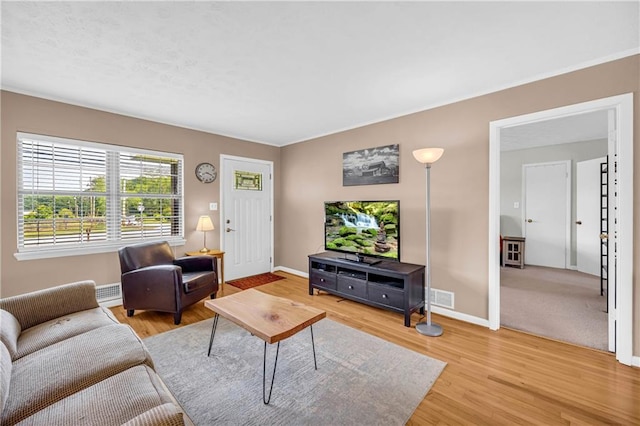 living room featuring baseboards, visible vents, and light wood-type flooring