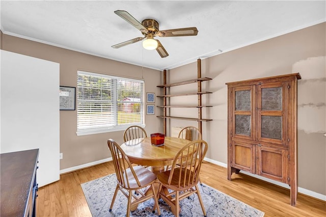 dining room with crown molding, baseboards, ceiling fan, and light wood finished floors