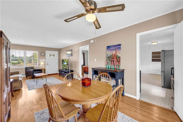 dining area with baseboards, a ceiling fan, and light wood-style flooring