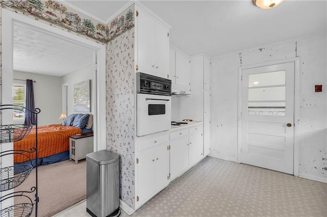 kitchen featuring baseboards, light floors, white cabinets, and oven