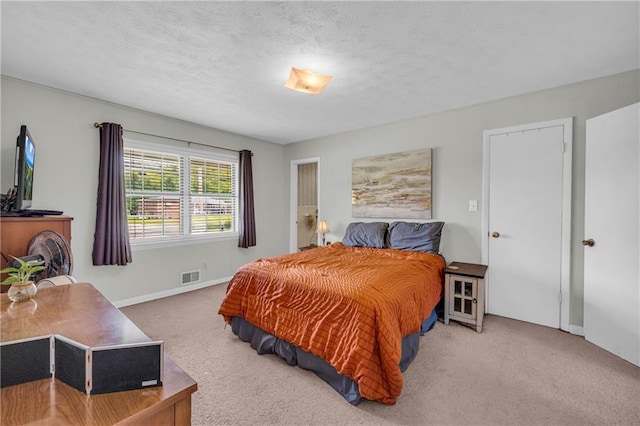 carpeted bedroom with visible vents, a textured ceiling, and baseboards