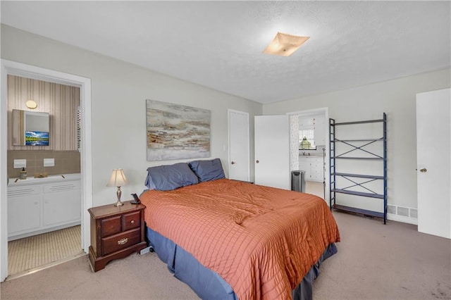 bedroom featuring light colored carpet and ensuite bath