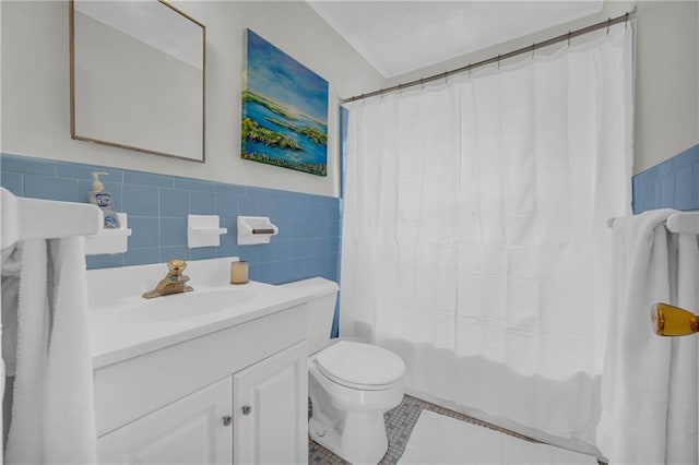 full bathroom featuring tile patterned flooring, vanity, wainscoting, toilet, and tile walls