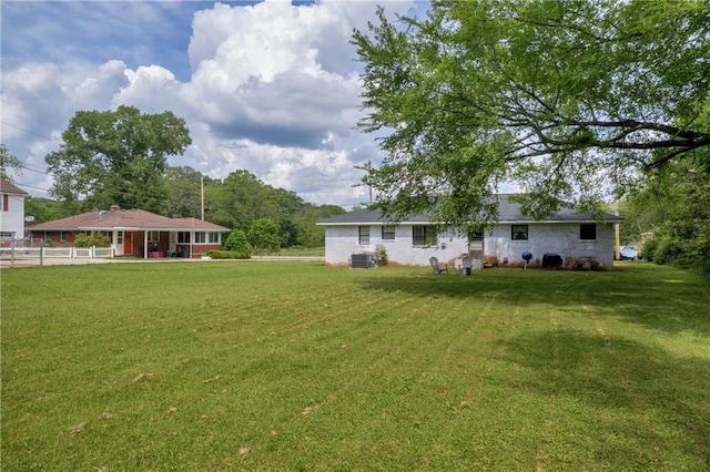 rear view of house with a lawn, fence, and central air condition unit