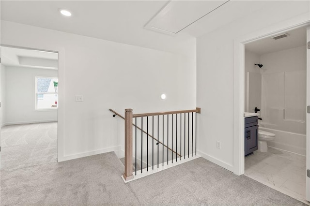 hallway featuring light colored carpet, baseboards, visible vents, and an upstairs landing