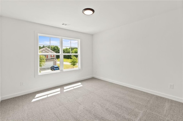 spare room featuring carpet floors, visible vents, and baseboards