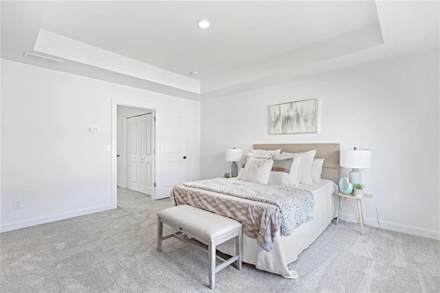 carpeted bedroom featuring a raised ceiling, visible vents, and baseboards