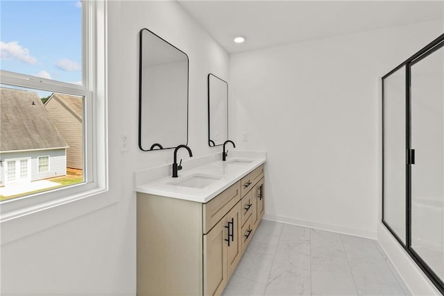 bathroom with double vanity, marble finish floor, baseboards, and a sink