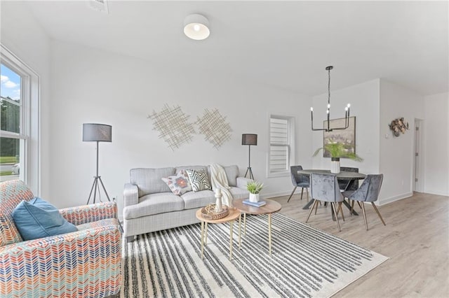 living room featuring a chandelier, light wood-type flooring, and baseboards