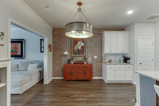 kitchen featuring light stone countertops, visible vents, white cabinets, and dark wood-style flooring