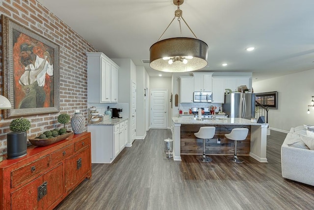 kitchen with stainless steel appliances, baseboards, decorative backsplash, dark wood-style floors, and a kitchen bar