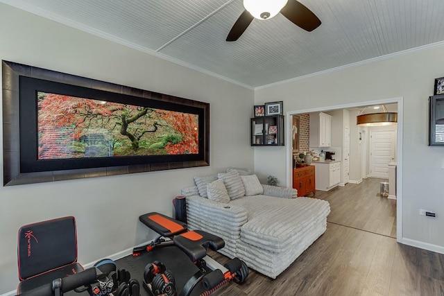 interior space with ceiling fan, crown molding, baseboards, and wood finished floors