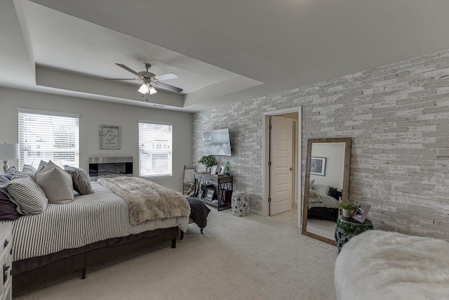 bedroom with a tray ceiling, light colored carpet, and ceiling fan