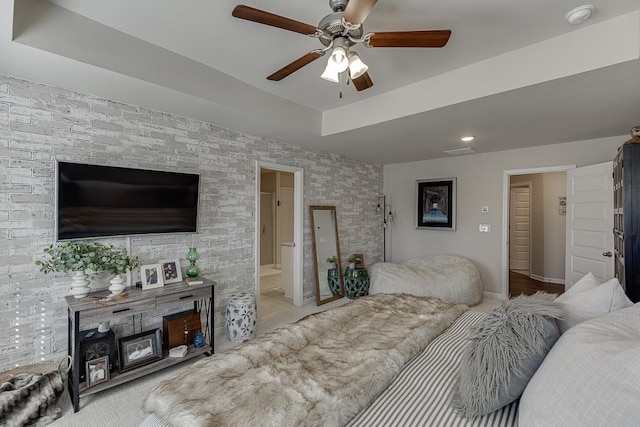 bedroom with ceiling fan, connected bathroom, visible vents, baseboards, and a raised ceiling