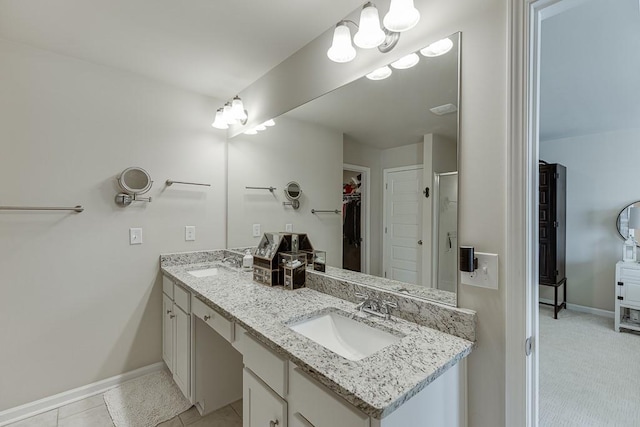 bathroom with a spacious closet, baseboards, and a sink