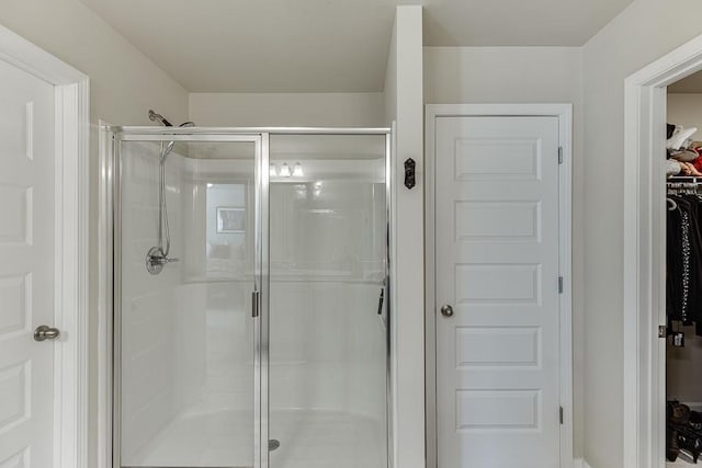 full bath featuring a shower stall and a spacious closet