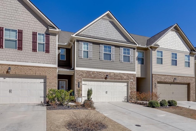 view of property featuring a garage, stone siding, concrete driveway, and brick siding