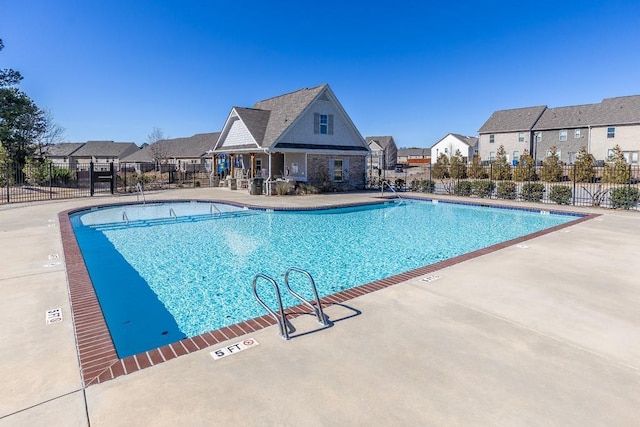 community pool with a patio area, a residential view, and fence