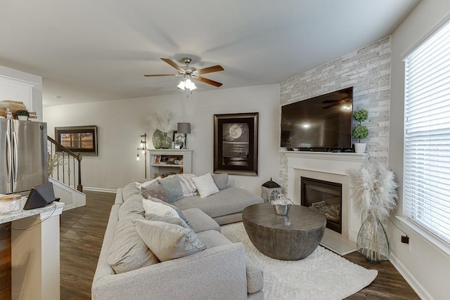 living room with a ceiling fan, a fireplace, dark wood finished floors, and stairs