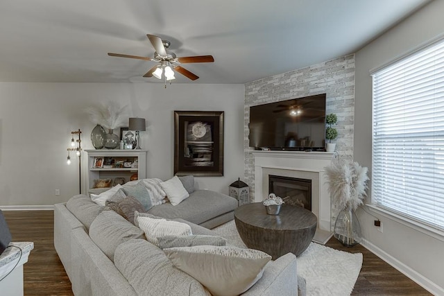 living room with a healthy amount of sunlight, a large fireplace, baseboards, and dark wood finished floors