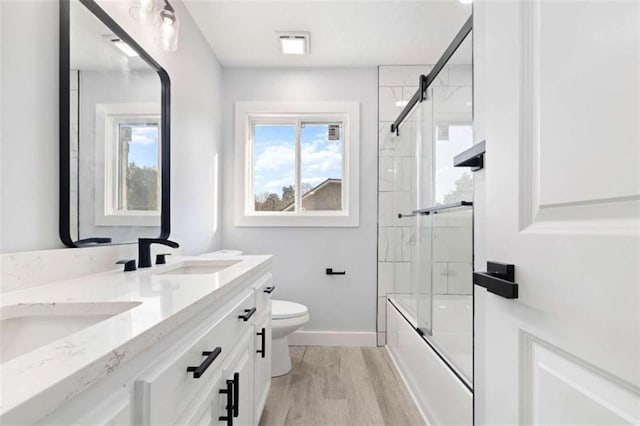 full bathroom with toilet, vanity, shower / bath combination with glass door, and hardwood / wood-style floors