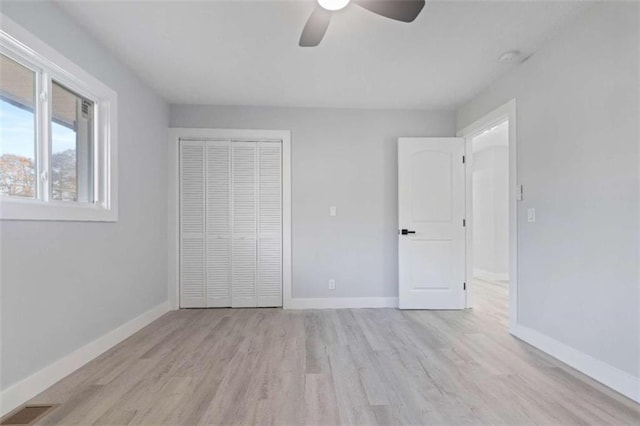 unfurnished bedroom featuring light hardwood / wood-style floors, a closet, and ceiling fan