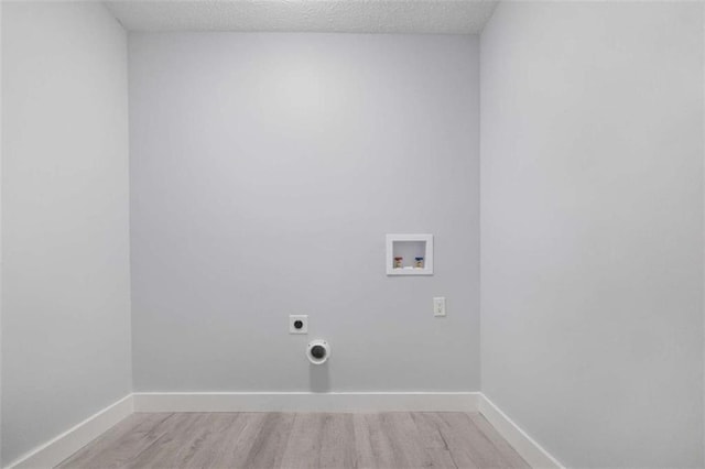 laundry area featuring a textured ceiling, hookup for a washing machine, light hardwood / wood-style flooring, and electric dryer hookup