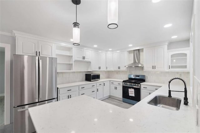 kitchen featuring appliances with stainless steel finishes, pendant lighting, sink, white cabinets, and wall chimney range hood