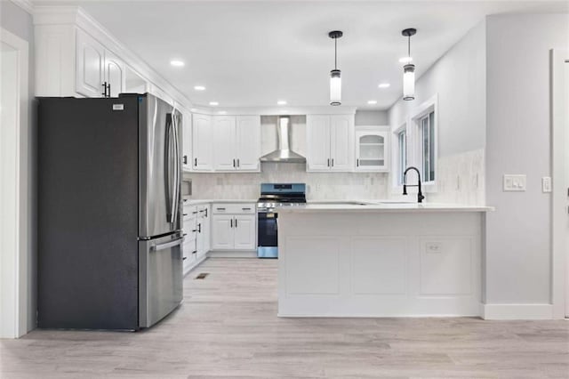 kitchen with white cabinetry, appliances with stainless steel finishes, decorative light fixtures, and wall chimney range hood