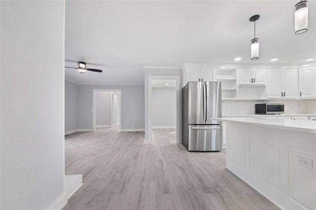 kitchen with white cabinetry, crown molding, hanging light fixtures, appliances with stainless steel finishes, and light hardwood / wood-style floors