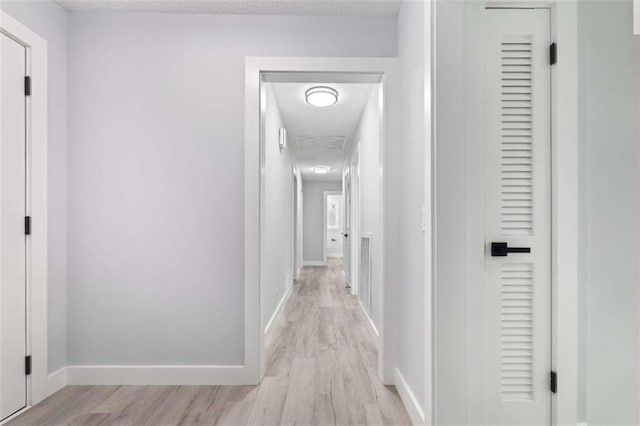 hall with light hardwood / wood-style floors and a textured ceiling