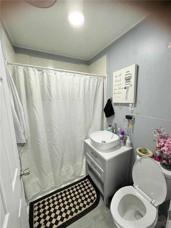 bathroom featuring hardwood / wood-style flooring, vanity, toilet, and tile walls