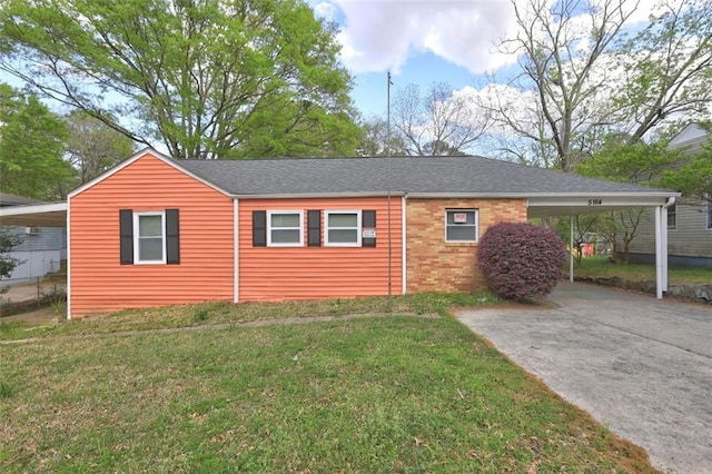 view of front of home with brick siding, a front lawn, an attached carport, and driveway