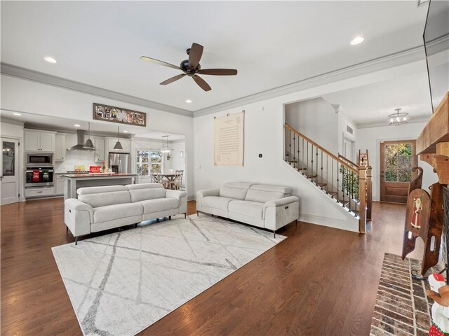 living room with hardwood / wood-style floors, ceiling fan with notable chandelier, crown molding, and a healthy amount of sunlight