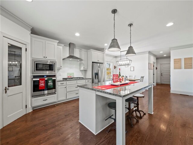 kitchen featuring wall chimney exhaust hood, white cabinetry, and stainless steel appliances