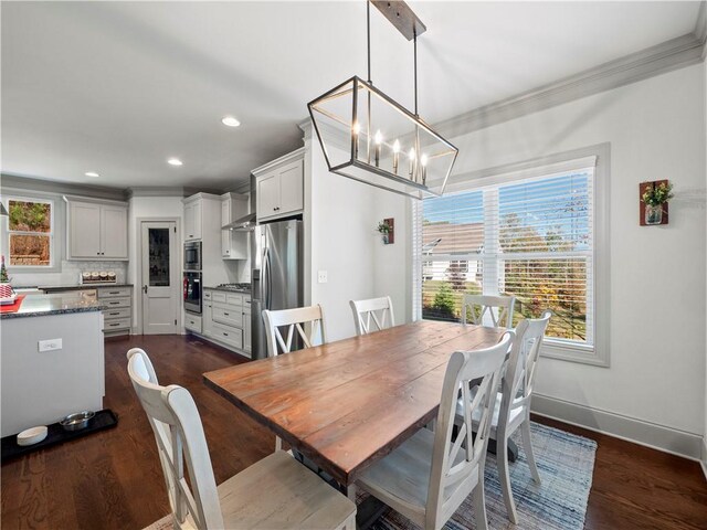 dining space with dark hardwood / wood-style floors, crown molding, and a chandelier