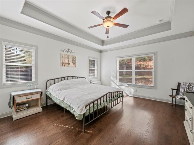 bedroom featuring ornamental molding, a tray ceiling, ceiling fan, and dark wood-type flooring