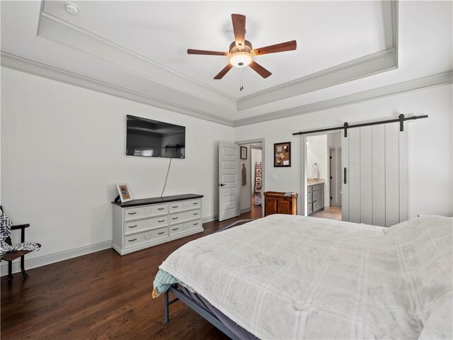 bedroom with a barn door, a tray ceiling, ceiling fan, and ensuite bathroom