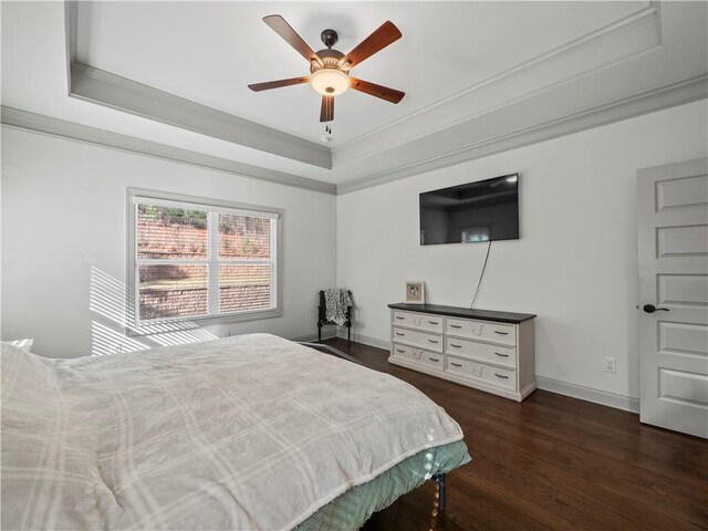 bedroom with ornamental molding, dark hardwood / wood-style floors, ceiling fan, and a tray ceiling