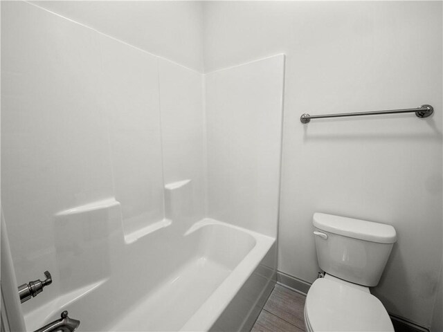 bathroom featuring bathing tub / shower combination, hardwood / wood-style flooring, and toilet