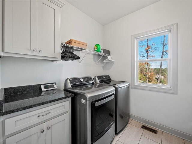 laundry room with cabinets, washer and clothes dryer, and light tile patterned flooring