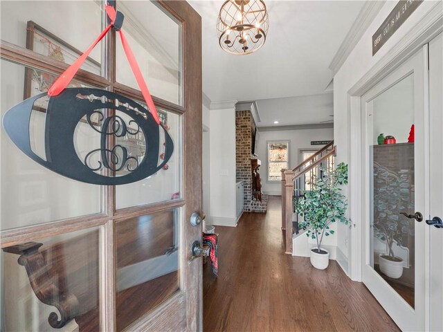 entryway with ornamental molding, dark wood-type flooring, and a chandelier