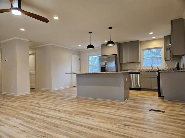 kitchen featuring visible vents, a center island, stainless steel appliances, gray cabinetry, and light wood-style floors