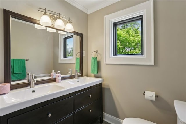 bathroom featuring toilet, crown molding, double vanity, and baseboards