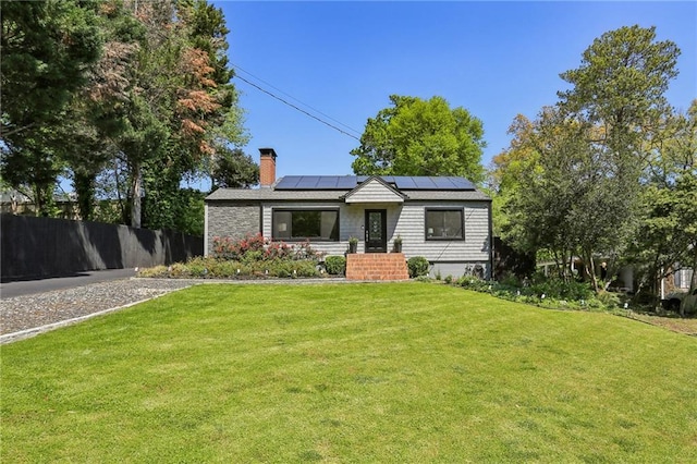 view of front of house featuring roof mounted solar panels and a chimney