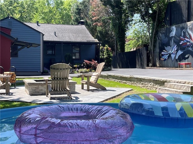 outdoor pool with an outdoor fire pit, a patio, and fence