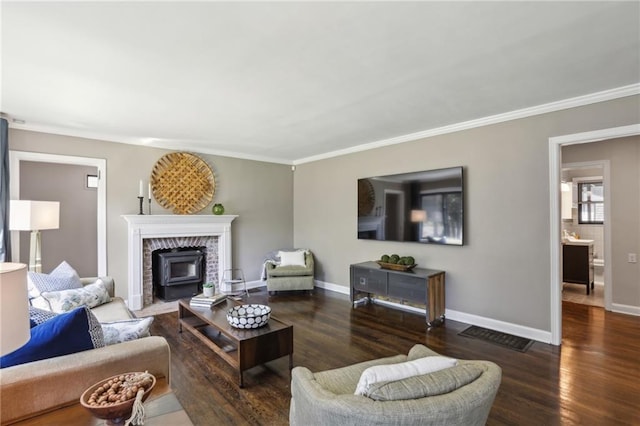 living room featuring wood finished floors, ornamental molding, baseboards, and a wood stove
