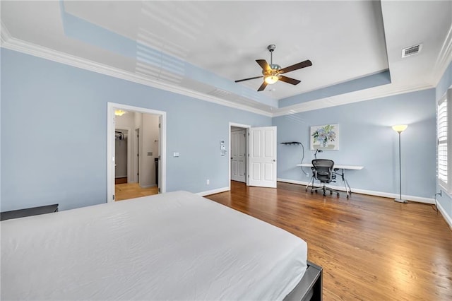 bedroom featuring a raised ceiling, ceiling fan, crown molding, and wood-type flooring