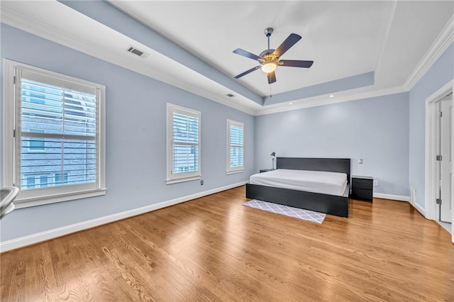 bedroom featuring a tray ceiling, ceiling fan, light hardwood / wood-style flooring, and crown molding