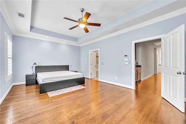 bedroom featuring light hardwood / wood-style floors, ceiling fan, crown molding, and a tray ceiling